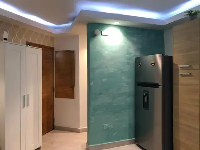 a kitchen with a green wall with a refrigerator at Estancia Riviera Colonial I in Santo Domingo