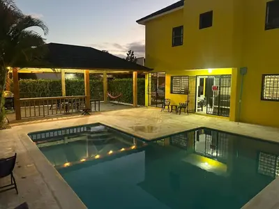 a house with a swimming pool in front of a house at Playa Dorada Mountainview Villa in San Felipe de Puerto Plata