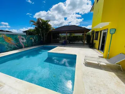 a swimming pool in front of a yellow house at Playa Dorada Mountainview Villa in San Felipe de Puerto Plata