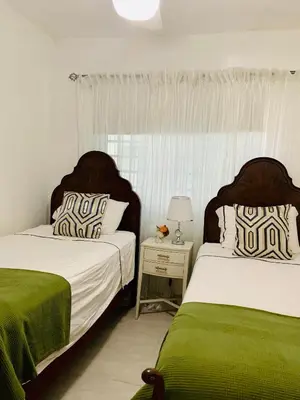a bedroom with two beds with green and white sheets at Beautiful & Comfortable Apartment near Colonial Zone in Santo Domingo