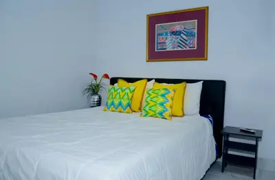 a bedroom with a white bed with colorful pillows at Rosil Place in San Felipe de Puerto Plata
