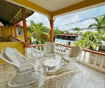 a balcony with white chairs and tables and palm trees at Apartmenthotel Michaela in Sosúa