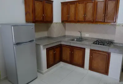 a kitchen with a white refrigerator and wooden cabinets at Residence Meridiana in Juan Dolio