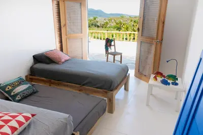 a bedroom with two beds and a door to a balcony at Casa Blava with AC in Las Galeras