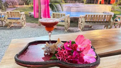 a drink and flowers on a table with a drink at CHALET TROPICAL Hotel & Pool Bar Restaurant in Las Galeras