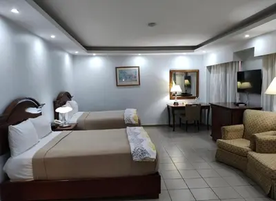 a hotel room with two beds and a chair and a desk at Micro Hotel Condo Suites in Santo Domingo