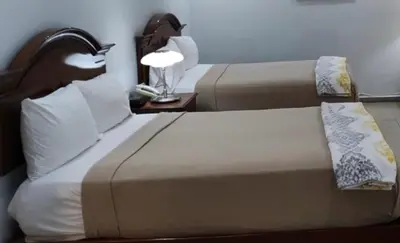 two beds in a hotel room with a lamp on a table at Micro Hotel Condo Suites in Santo Domingo