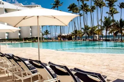 a pool with chairs and an umbrella next to a swimming pool at Beach Apartment - Marbella, Juan Dolio!! Getaway Offer!! in Juan Dolio