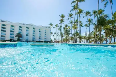 a swimming pool with palm trees in front of a hotel at Beach Apartment - Marbella, Juan Dolio!! Getaway Offer!! in Juan Dolio