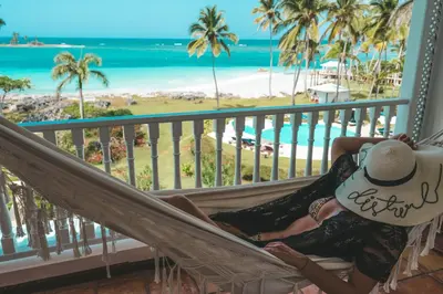 a woman sitting in a hammock on a balcony overlooking the beach at Hotel Villa Serena in Las Galeras