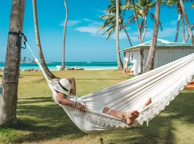 a woman laying in a hammock on the beach at Hotel Villa Serena in Las Galeras