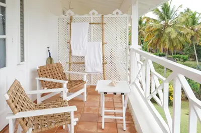 a white porch with chairs and a table at Hotel TODOBLANCO, Las Galeras, SAMANA in Las Galeras