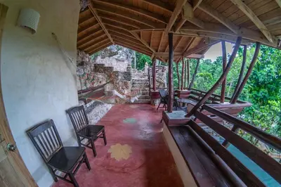 an attic room with chairs and a stone wall at Paraiso Caño Hondo in Los Guineos Perdidos