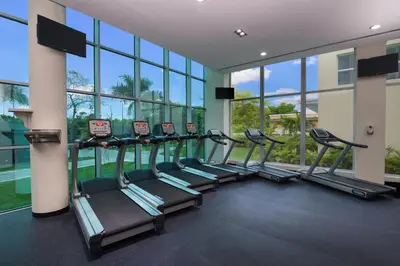 a row of treadmills in a gym with windows at Iberostar Selection Coral Bavaro - All Inclusive in Punta Cana