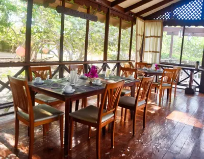 a dining room with tables and chairs and windows at El Morro Eco Adventure Hotel in San Fernando de Monte Cristi