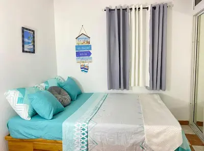 a bed with blue pillows in a room at Dre Broeders Apartments Juan Dolio in Juan Dolio