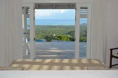 a bedroom with a view of the ocean through a window at Villa Noria in Las Terrenas