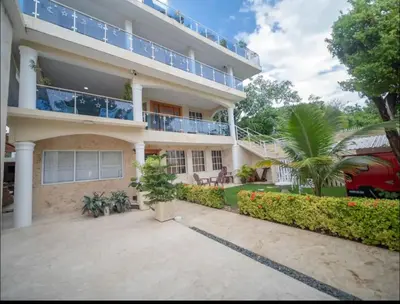 a large apartment building with a patio and palm trees at Home W Private Hot Tub, Near Everything in Sosua Center in Sosúa