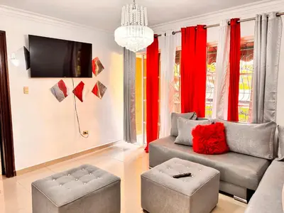 a living room with a couch and red curtains at 1Dom Rep - Huge cozy 3 bedrooms - close to all transportation Jacobo Majluta - Residencial Paradise V Colina Arroyo 1 in Santo Domingo