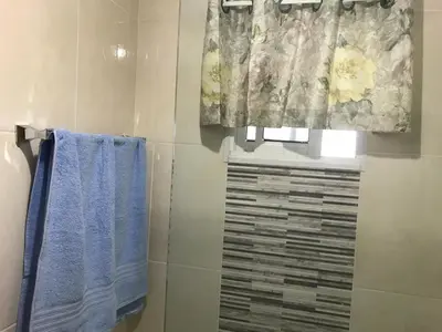 a bathroom with a shower with blue towels and a window at CONFORTABLE first floor en santiago RD in Santiago de los Caballeros