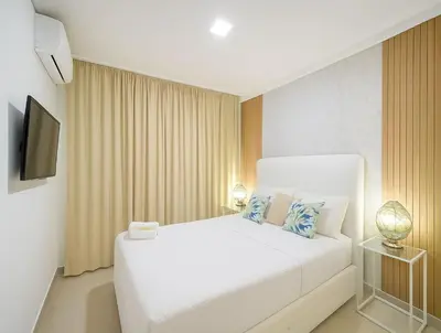 a bedroom with a white bed and a television at Cozy 2br-2bt Apt Near The Beach And Main Street in Sosúa