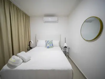 a bedroom with a large white bed with a mirror at Cozy 2br-2bt Apt Near The Beach And Main Street in Sosúa