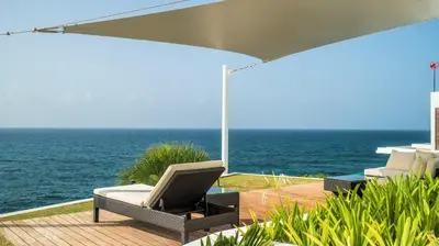 a patio with a chair and an umbrella and the ocean at Cap el Limon Luxury Villas in El Limón