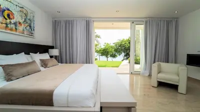 a bedroom with a large bed and a chair at Cap el Limon Luxury Villas in El Limón