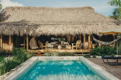 a resort with a swimming pool and a thatch roof at Bungalow with pool and Air Conditioning near playa Macao in Punta Cana