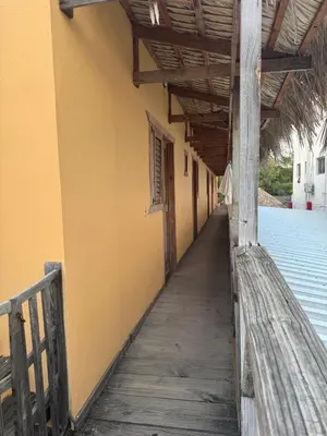 a wooden walkway next to a yellow building at Hotel Loro Tuerto in Santa Cruz de Barahona