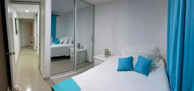 a white bed with blue pillows in a bedroom at Fully Equipped New 3br Apt dt 2mins To The Beach in Sosúa