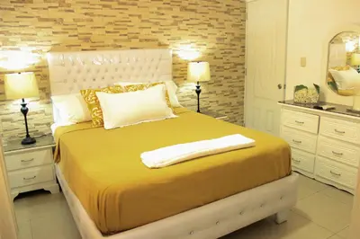 a bedroom with a large bed with yellow sheets and pillows at Fully Equipped New 3br Apt dt 2mins To The Beach in Sosúa