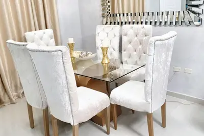 a dining room with a glass table and two white chairs at Spacious house in Santo Domingo Este with garden in Santo Domingo