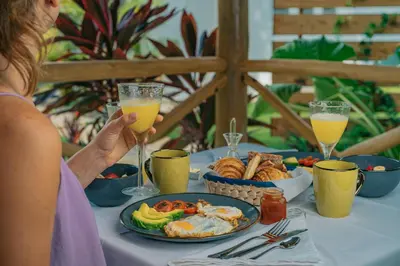 a woman sitting at a table with a plate of food at PUNTA POPY BOUTIQUE HOTEL - Adults Only in Las Terrenas