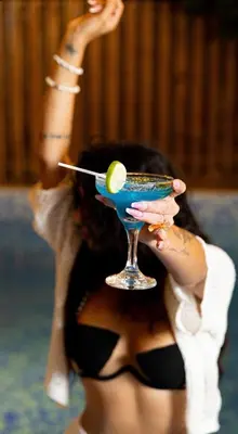 a woman in a bikini holding a blue drink at Casa Docia Hotel in Santa Bárbara de Samaná
