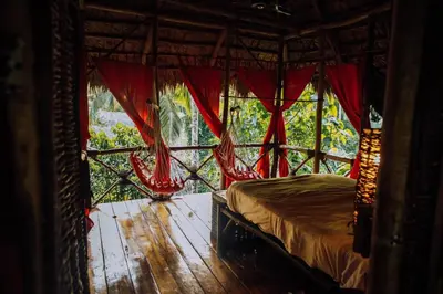 a bedroom with a bed with red curtains and a window at Dominican Tree House Village in El Valle