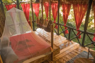 a hammock in a tree house with red drapes at Dominican Tree House Village in El Valle