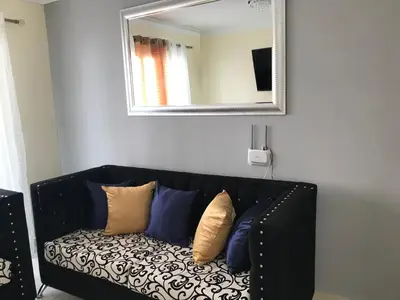 a black couch with pillows sitting under a mirror at cómodo first floor in Santiago de los Caballeros