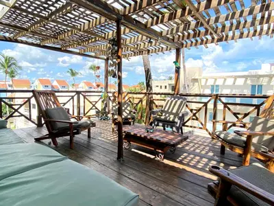 a wooden deck with chairs and a bench on a balcony at Private Rooms-Art Punta Cana in Punta Cana