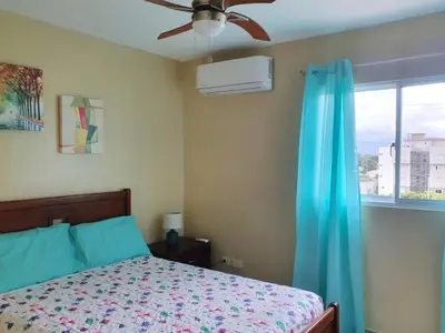 a bedroom with a bed with a ceiling fan and a window at Paraiso de verano in Santiago de los Caballeros