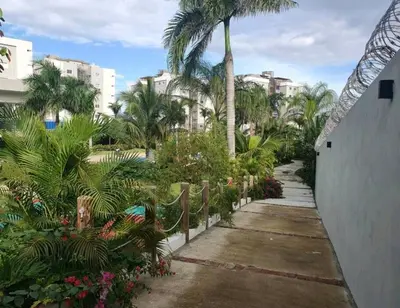 a walkway with palm trees and plants and buildings at Paraiso de verano in Santiago de los Caballeros
