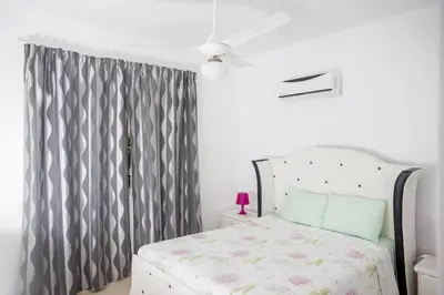 a bedroom with a bed with a gray curtain at Bela Villa Apartment IDA in Bayahibe