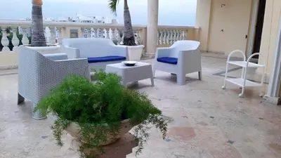 a balcony with white chairs and a table and palm trees at Elegant apartment with Jacuzzi in Boca Chica - 200 m² in Boca Chica