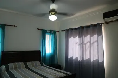 a bedroom with a bed with blue curtains and a window at Apartamento Amueblado Amplio Tranquilo Privado Como tu lo Mereces in Santiago de los Caballeros
