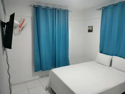 a bedroom with a bed with blue curtains and a fan at Hotel Yamir in Santa Cruz de Barahona