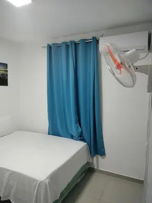 a small room with a bed and a blue curtain at Hotel Yamir in Santa Cruz de Barahona