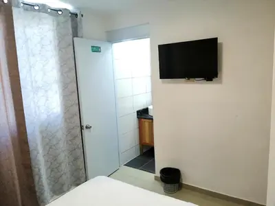 a bathroom with a shower and a television on the wall at Hotel Yamir in Santa Cruz de Barahona