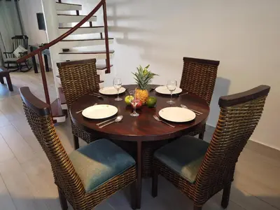 a dining room table with chairs and a wooden table with wine glasses at Nanny Estates Cabarete kiters Condo C-6 in Cabarete