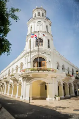 a large white building with a clock tower at Malecon Premium Rooms & Hotel in Santo Domingo
