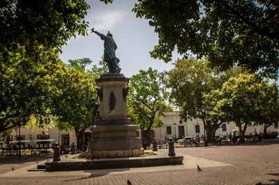 a statue of a man on a pedestal in a park at Malecon Premium Rooms & Hotel in Santo Domingo
